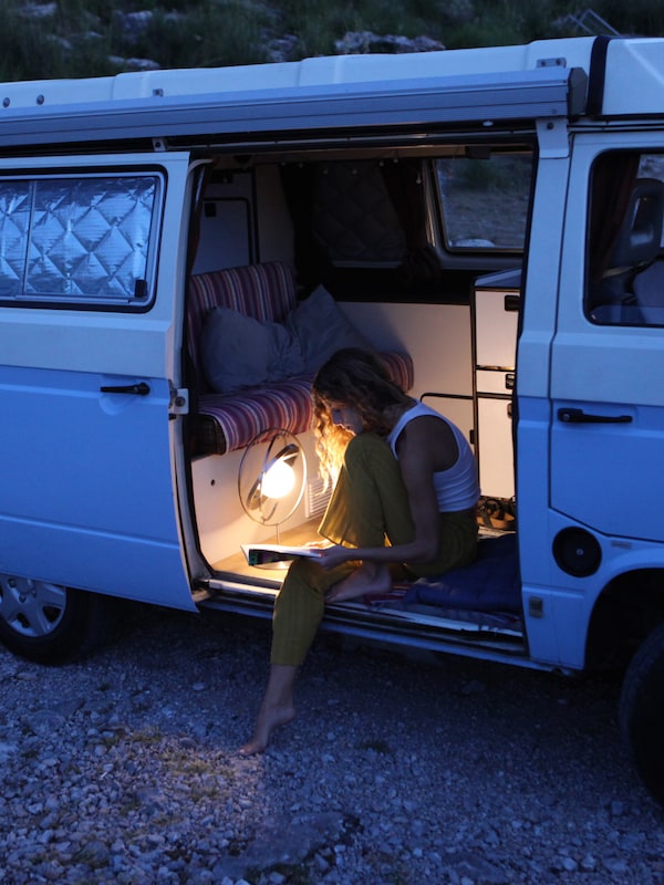 这是黄昏。开幕式一个人坐在一辆面包车看书的SAMMANLANKAD LED太阳能台灯。