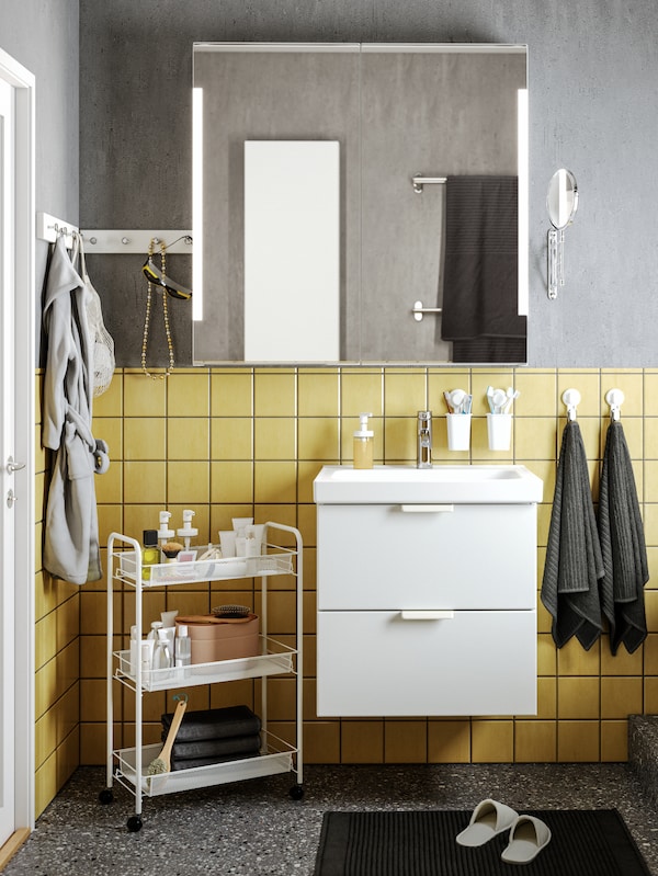 浴室与灰色墙混凝土的效果,黄色的瓷砖,白猛然站起身,下面有两个抽屉STORJORM镜子。