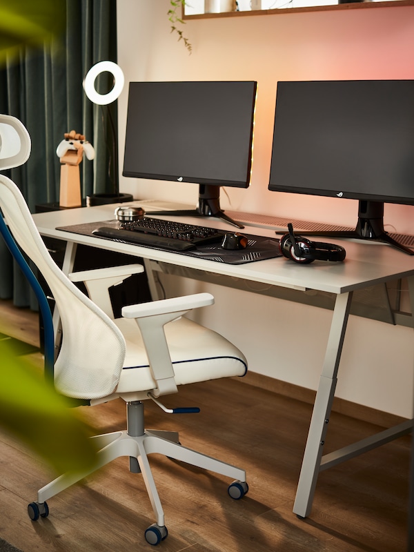 一个UTESPELARE游戏桌和一个白人MATCHSPEL游戏椅在家里工作空间有两个电脑显示器。