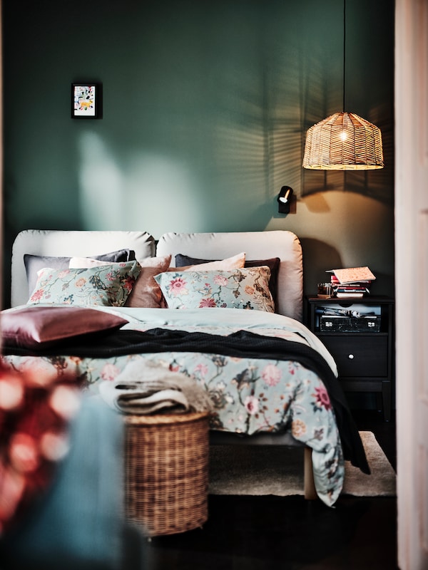 SAGESUND软垫床穿着浅灰绿色/多色NASSELKLOCKA床单IDANAS床头柜的旁边。