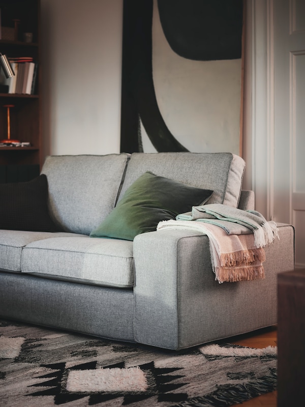 一个KIVIK 2-seat沙发垫子和抛出站在客厅的一个角落里与前部flatwoven地毯。