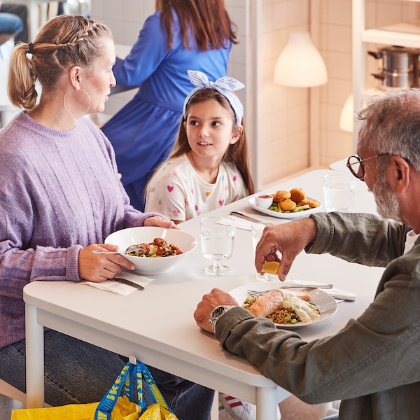 两个成人和一个孩子一起享受一顿饭坐在白色的表在瑞典宜家的餐厅。亚博平台信誉怎么样