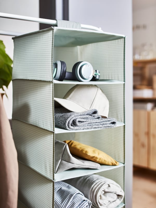STUK存储与7个隔间,拿着衣服,耳机,袋和床上用品,挂在白色MULIG衣架。