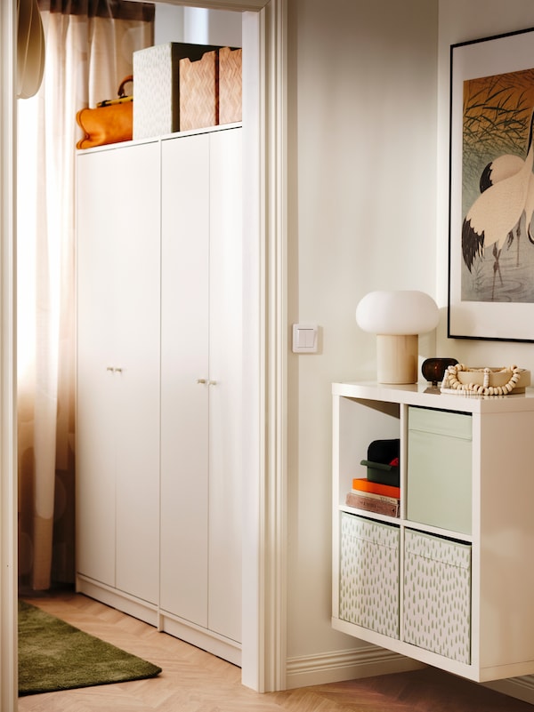 高光泽的白色KALLAX搁置单元安装在墙上的房间卧室旁边有两个KLEPPSTAD衣柜。