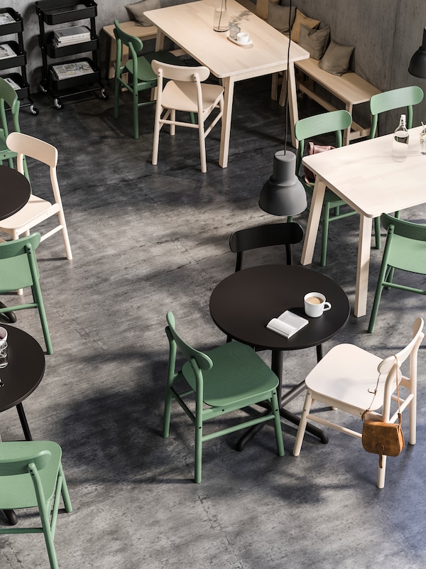 在einem Quadratische和runde Tische Cafebereich,阿莱麻省理工学院RONNINGE Stuhlen。Große HEKTAR Hangeleuchten信德的der盖befestigt。