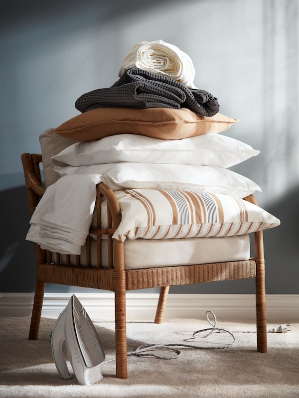 床上用品在白色ANGSLILJA床单,深灰色的床罩和黑米色靠垫上堆着HOLMSTA / FROKNABO扶手椅。