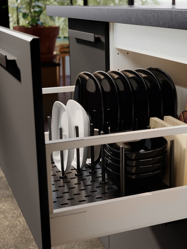 黑色和白色的碗和盘子整齐的叠放在厨房抽屉和一个UPPDATERA木栓板抽屉组织者。
