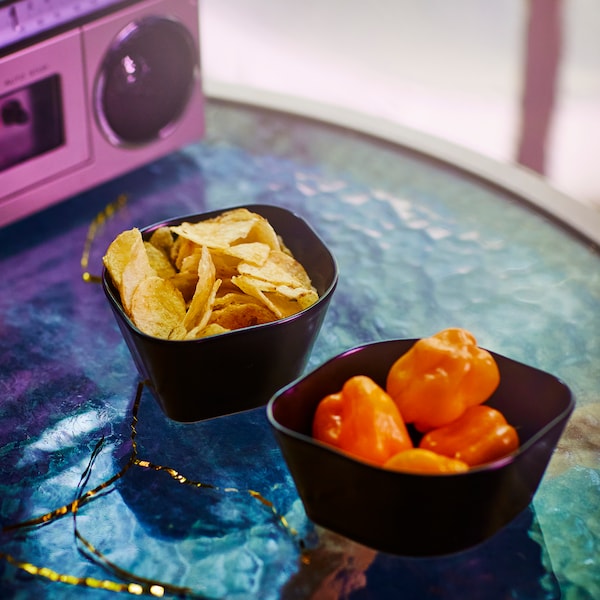 两个黑OMSESIDIG服务在陶瓷碗装满小辣椒和玉米片彩色玻璃桌子。