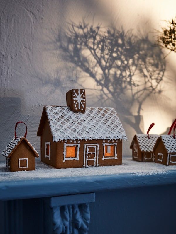 一个VINTERSAGA姜饼屋和一个建在人造雪上的迷你姜饼屋装饰着一个灰色壁炉台。