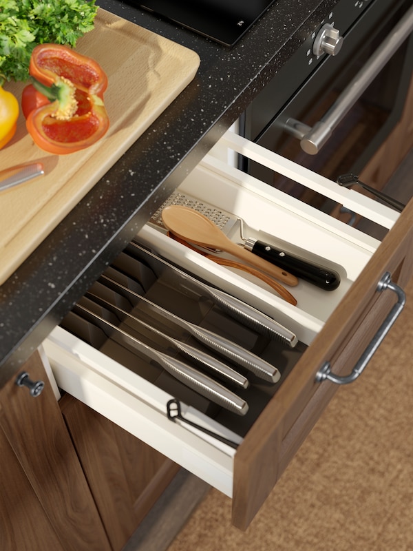 一个开放式厨房抽屉包含UPPDATERA与刀盘架,满是刀和其他厨房用具。