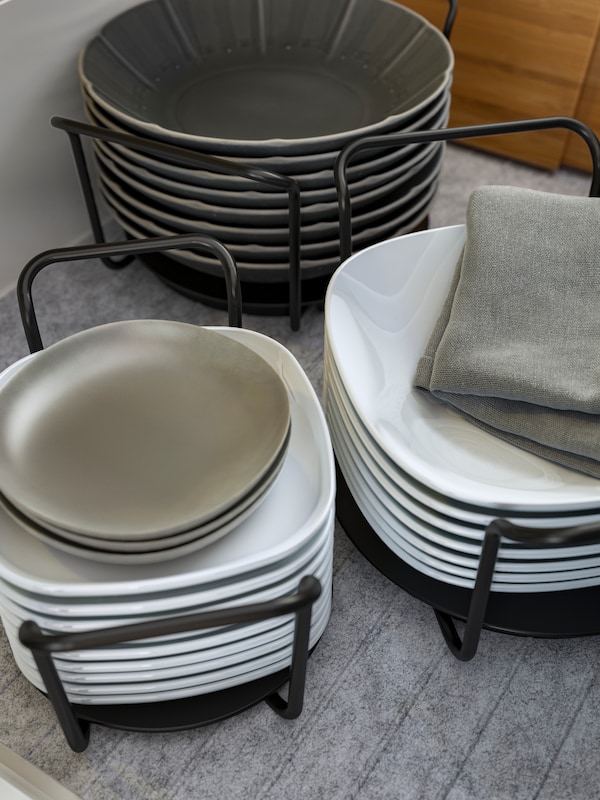UPPDATERA板持有人在无烟煤成堆的盘子和深盘子在白色和灰色,灰色的布上。