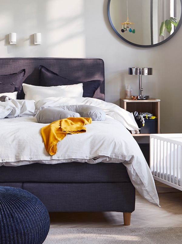 一个卧室DUNVIK深灰色的沙发床上,灰色/条纹被套和枕套,两个白人阅读灯和摇篮。