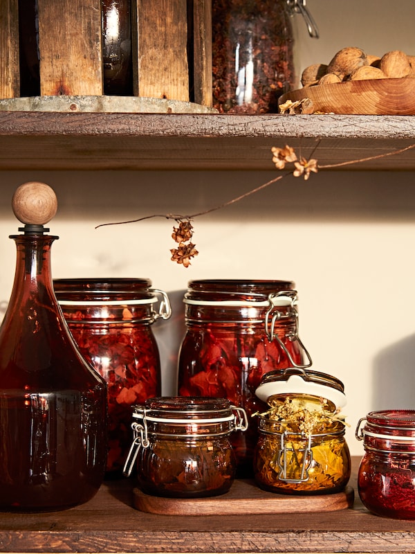 搁架持有KRÖSAMOS罐盖在红棕色和各种其他透明玻璃和彩色KRÖSAMOS罐和瓶子。
