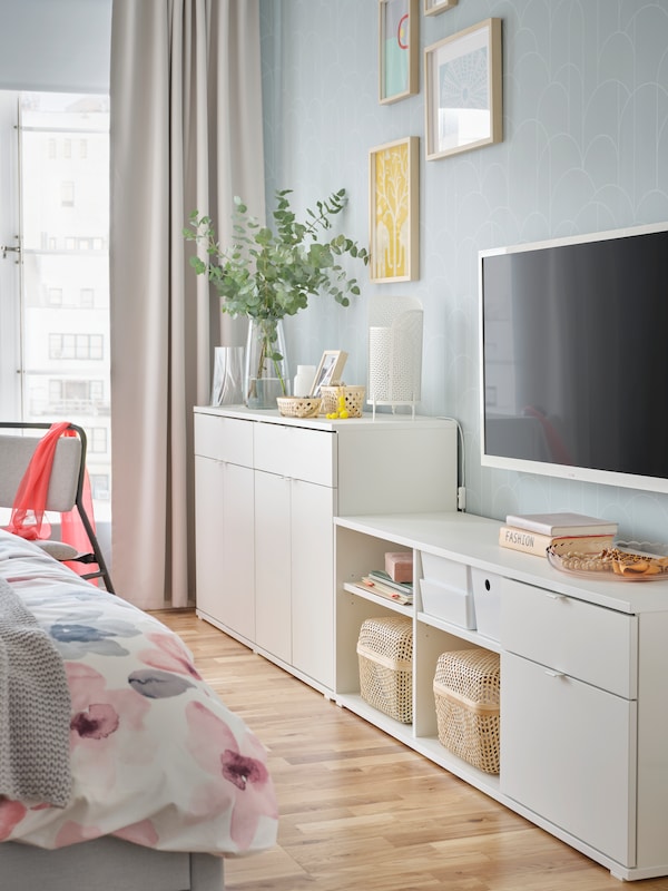 白色VIHALS电视上靠墙站在卧室安装在墙上的电视和一个白色VIHALS餐具柜。