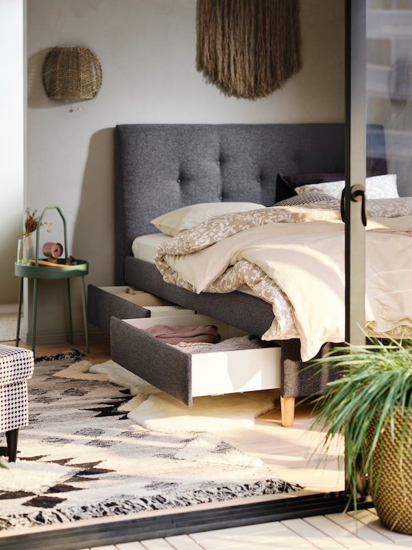 灰色软垫IDANAS床上覆盖着花和普通床单存储抽屉打开显示折叠纺织品。