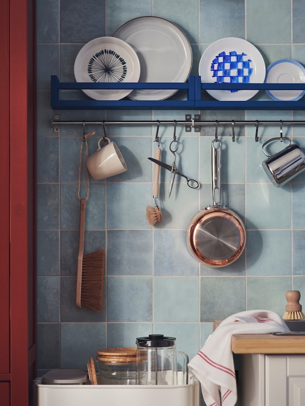 两个BEKVAM香料架,漆成蓝色,两个KUNGSFORS rails各种厨房用具挂在瓷砖墙上。