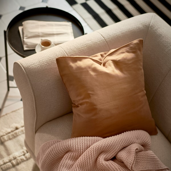 浅米色/棕色VISKAFORS 2-seat与一个棕色的沙发垫和淡粉色把站在flatwoven地毯。