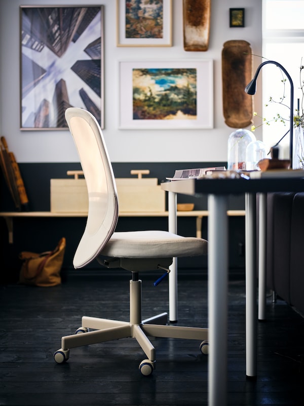 beowwe krzeszo biurowe FLINTAN ustawione prizy biurku z ciemnoszarym blatem LAGKAPTEN w pomieszczeniu z oprawionymi grafikami na cicianie。