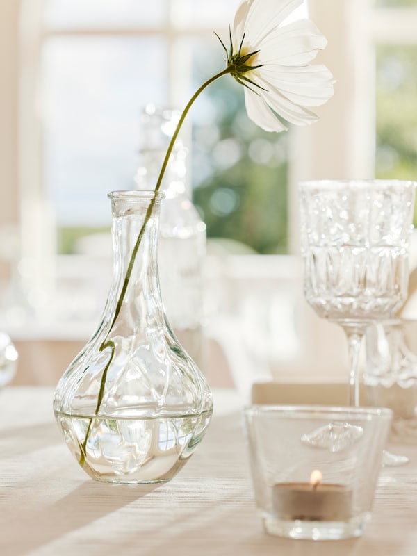 VILJESTARK清晰与单个白色花,花瓶一个GALEJ茶蜡持有人和SALLSKAPLIG酒杯放在桌上。