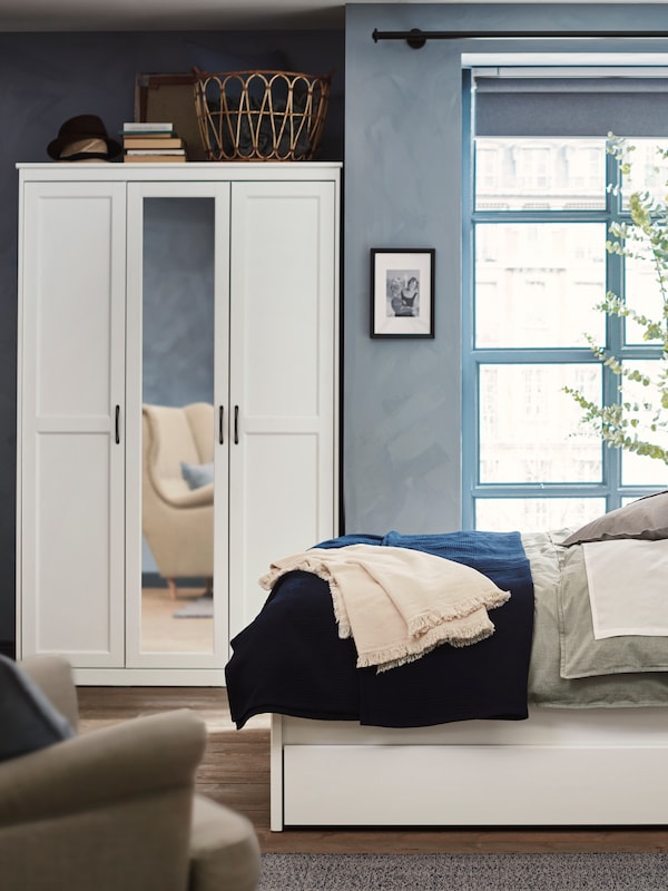 白色SONGESAND衣柜的镜子在床的附近一个蓝色的卧室。一把扶手椅是反映在它的镜子。