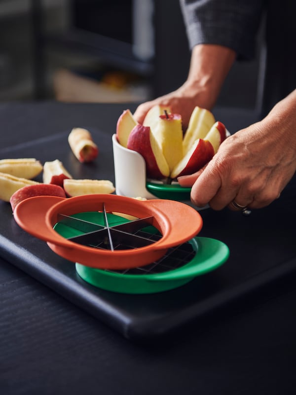 一些UPPFYLLD水果刀具在一组四个混合颜色,一个人的手切水果切一个苹果。