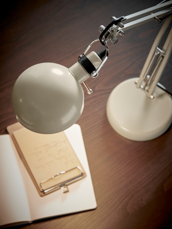 米色富彩工作灯站在一个棕色IDANAS办公桌,光一个笔记本和一个笔记本。