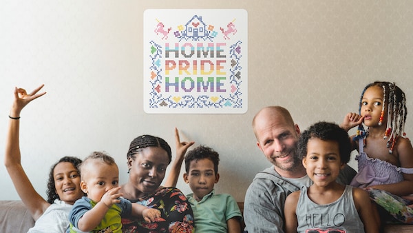 两个父母和五个孩子的家庭坐在沙发上的骄傲家背后墙上的标志。
