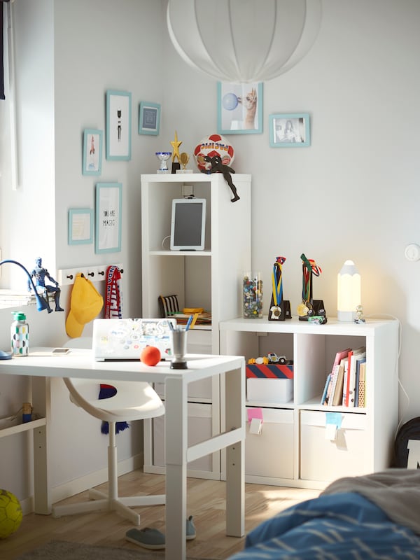 白色KALLAX搁置单元在孩子的房间里满是书籍,存储盒,玩具,一个研究领域。