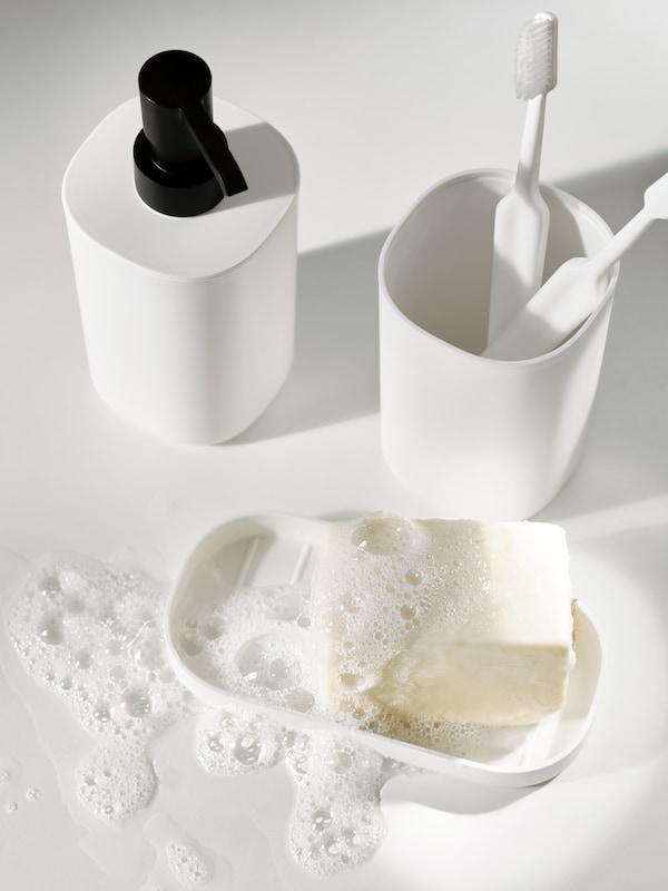 一套白色STORAVAN浴室有两个白色牙刷架和一块湿的白肥皂盘。