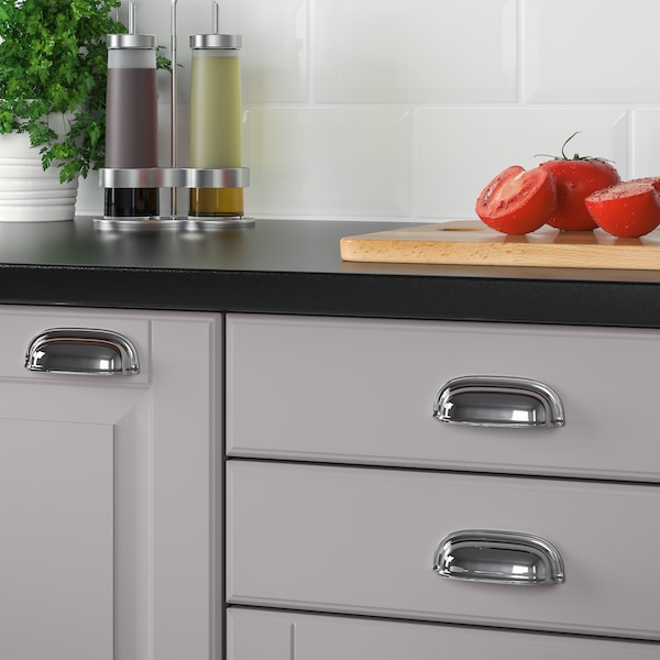 灰色的厨房配备ENERYDA镀铬处理。工作台面是油,醋和几片西红柿。