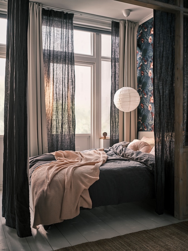 深灰色DYTAG窗帘和浅灰色MAJGULL房间黑暗的窗帘在床和白色REGOLIT吊灯上面。