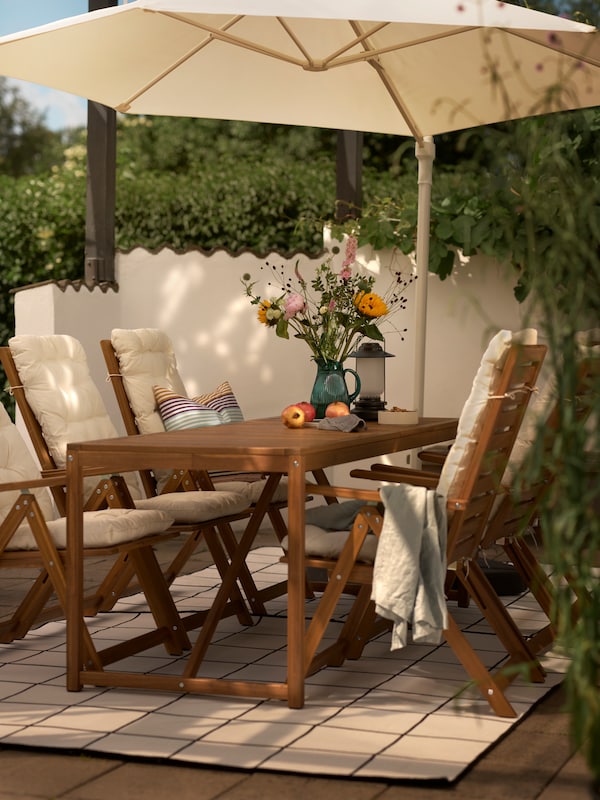 浅棕色的户外餐桌和六个躺椅上米色座位/靠垫,加上一个白色HOGON挂阳伞。