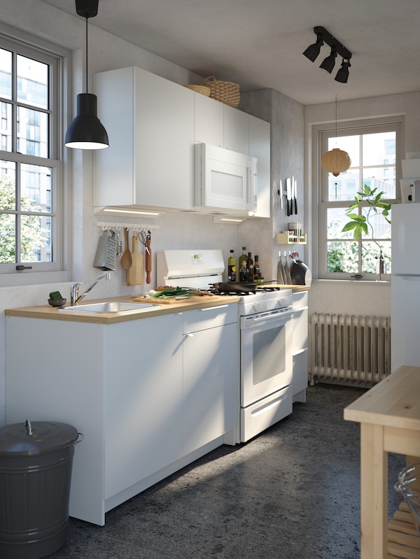 KNOXHULT厨房与各种项目在操作面白色,深灰色HEKTAR吊灯和厨房手推车。