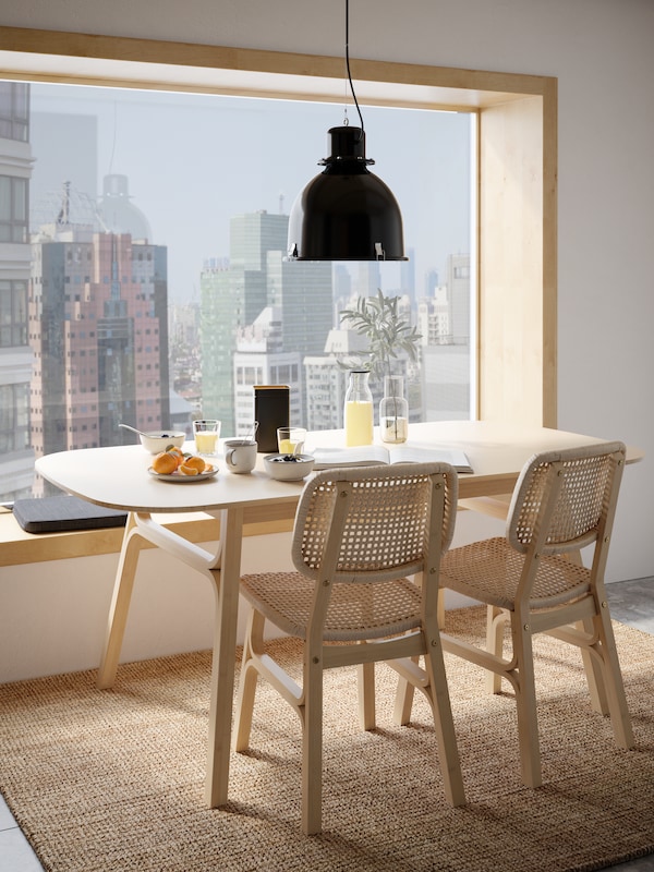 淡竹餐桌上的一个大窗口,一个城市来看,两个光竹椅子和早餐放在桌子上。
