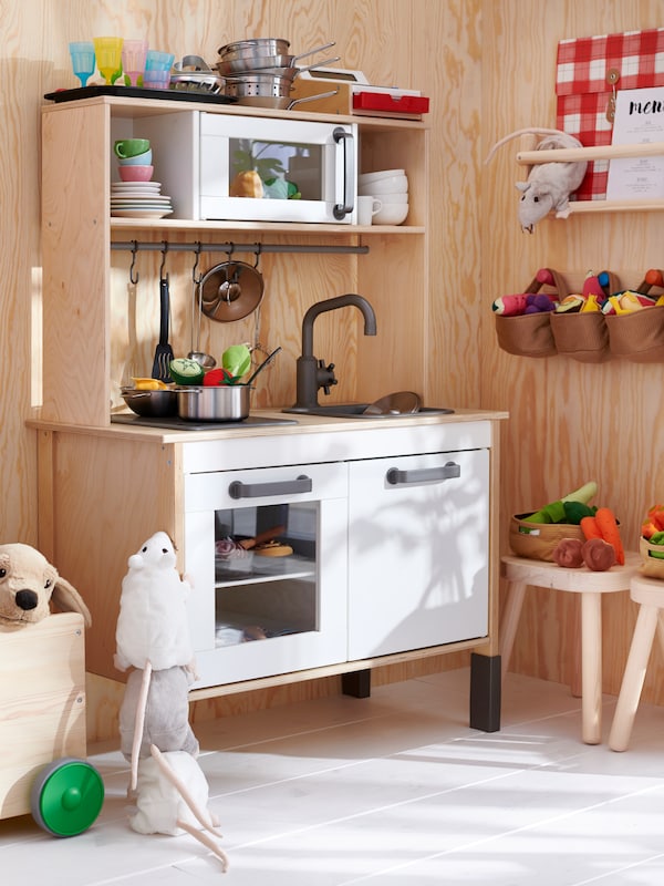 DUKTIG游戏与玩具厨房炊具、餐具和蔬菜站在房间的一个角落里。