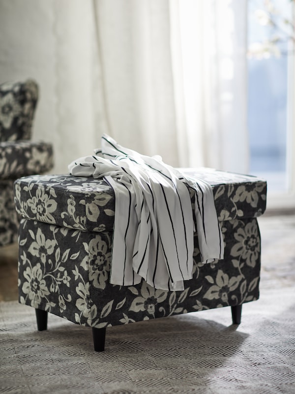 STRANDMON的脚凳,花卉Frorum沙发套站在地毯上在一个房间里有白色的窗帘。