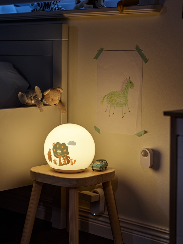 森林图案BRUMMIG LED台灯FLISAT儿童凳子,加上TRADFRI无线运动传感器在墙上。
