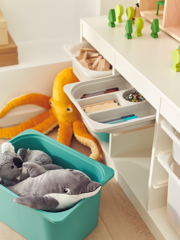 绿松石TROFAST存储盒拿着玩具在地板上的单位充满TROFAST存储容器的混合体。