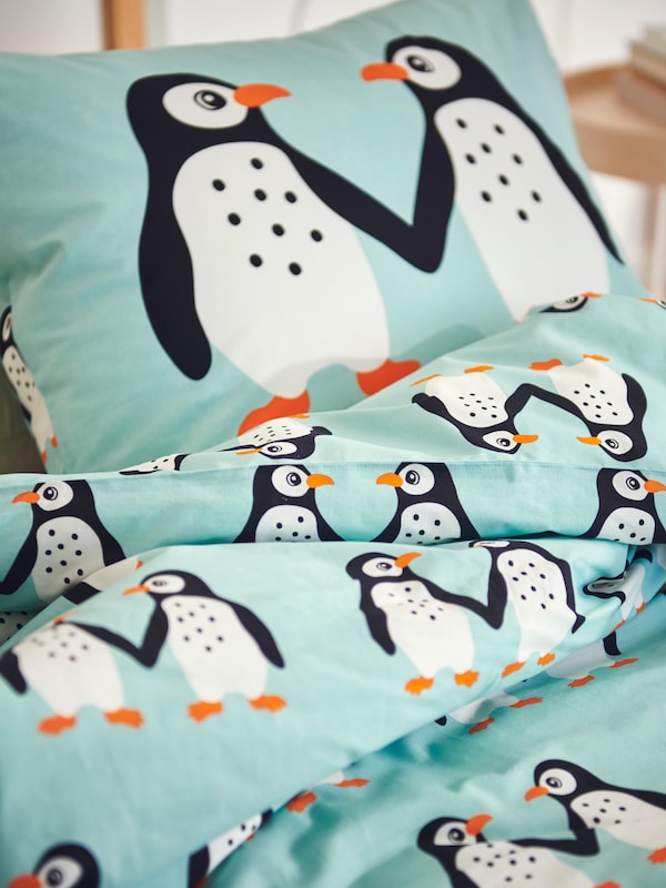 枕头、羽绒被BLAVINGAD枕套,被套在一个孩子与一只企鹅模式躺在床上。