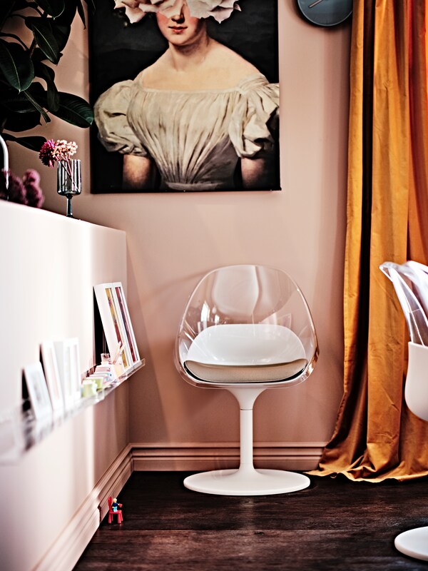 白色BALTSAR转椅在一堵墙后,打印以下,旁边一个灰色OMBONAD酒杯与鲜花。