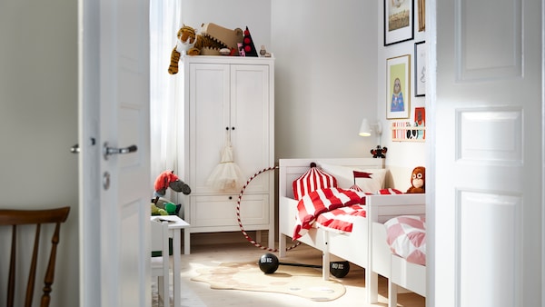 SUNDVIK可扩展与SUNDVIK儿童床在孩子的卧室衣柜的衣服。有明亮的彩色表红色,白色和粉红色的床和玩具在房间里。