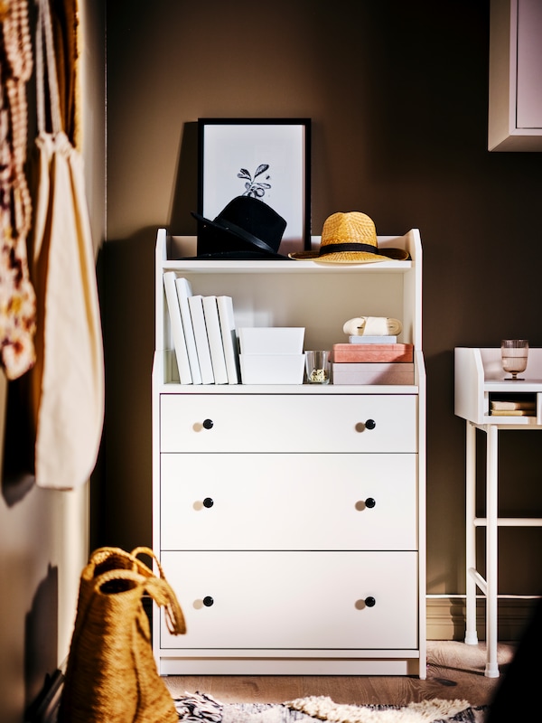 白色HAUGA衣柜在卧室装饰物品和书籍上HAUGA梳妆台旁边桌子上。