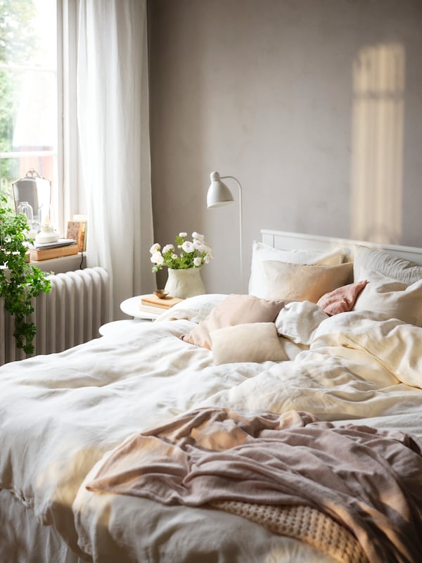 白色SONGESAND床上用白色DYTAG床单在不同的颜色和其他纺织产品站在一个阳光明媚的卧室。