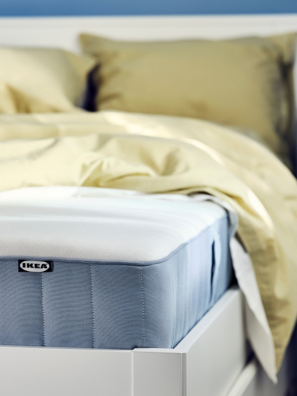 浅蓝色VESTEROY口袋里装有弹簧床垫一个白色的床上,穿着与光beige-green ANGSLILJA床单。