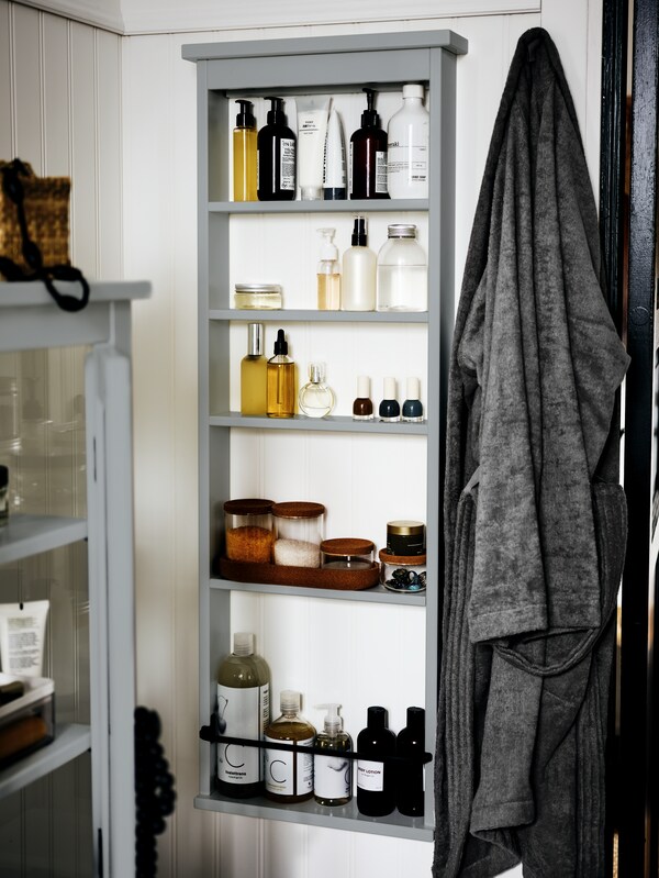 灰色HEMNES墙书架,拿着瓶子和各种浴室用品和HEMNES高内阁在灰色的玻璃门。