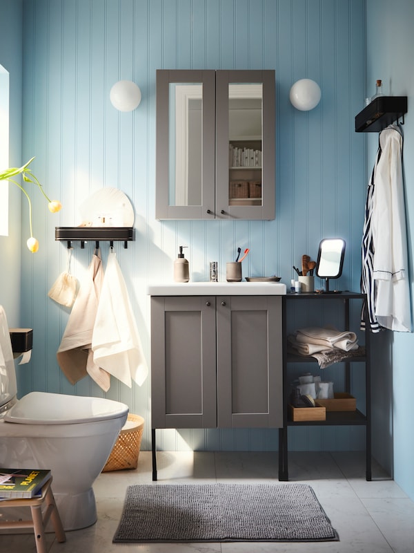 浴室用蓝色的墙壁,ENHET浴室家具,一个灰色的垫子,LILLASJON墙架5钩和白墙灯。