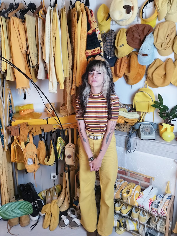 一个年轻女子穿着黄色是站在她的面前打开衣柜。它充满了黄色的衬衫,黄色的帽子,黄色的鞋子,和黄色的配件。