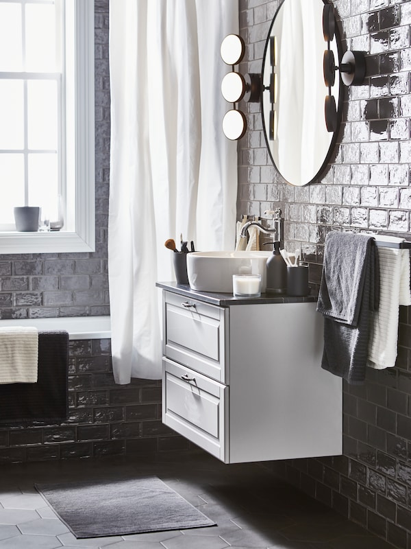 浴室有白色和深灰色的手,浴巾,白色BJARSEN浴帘,一轮黑色的镜子。