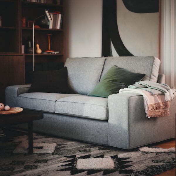双座KIVIK沙发有缓冲站在客厅的角落与它的前腿TANNISBY flatwoven地毯。
