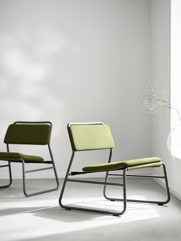 LINNEBACK容易椅子两个用黑色金属框架和Orrsta橄榄绿色覆盖面对不同的方向在一个房间里。